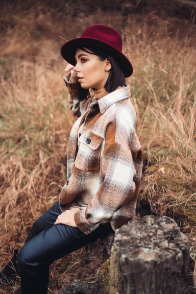 Sonbahar gününde güzel bir kadın. Güzellik ve moda. Sonbahar modası ve yaşam tarzı. Sıcak sonbahar kıyafetleri, şapka ve sarı eşarp giyen güzel bir kadın. Sonbahar havası. Açık havada şık bir kadın..