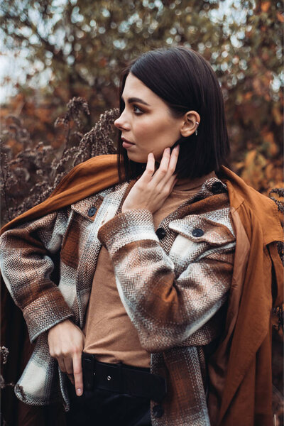 Beautiful elegant woman standing in a park in autumn