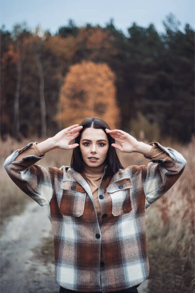 Young woman fashionably dressed in a dry autumn forest