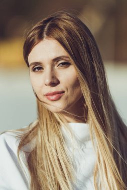 Güzel sarışın kadın portresi. Sahilde beyaz, kalın giysiler giyen moda kadını..