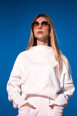 Güneşli bir günde kumların üzerinde beyaz elbiseler giymiş güzel, şık bir genç kadın.