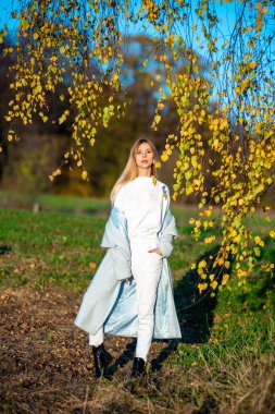 Sonbahar kıyafetleri içinde güzel bir kadın, açık havada, mavi gökyüzü arka planda.