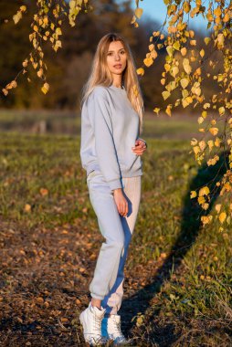 Sıcak sonbaharda, beyaz, sıcacık giysiler içinde güzel bir kadın.