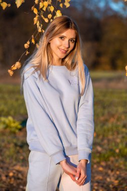 Sonbahar kıyafetleri içinde güzel bir kadın, açık havada, mavi gökyüzü arka planda.