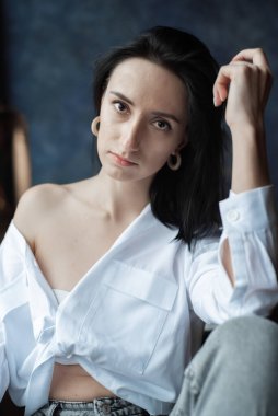 Ev ortamında genç bir kadın günlük giysiler giyiyor.