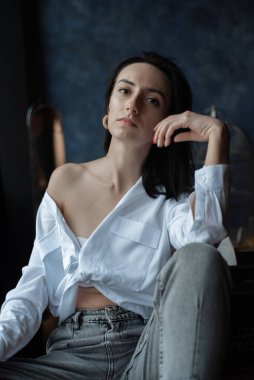 Ev ortamında genç bir kadın günlük giysiler giyiyor.