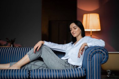 Ev ortamında genç bir kadın günlük giysiler giyiyor.