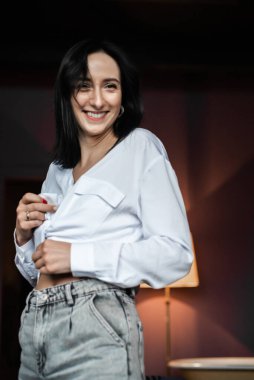 Ev ortamında genç bir kadın günlük giysiler giyiyor.