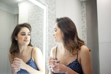 Aynanın yanındaki genç kadın, cilt bakımı sabah rutini.