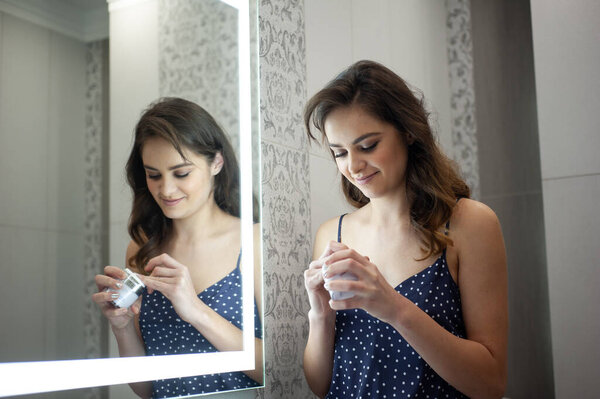 Young woman near the mirror, skin care morning routine