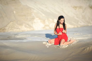 Güzel bir kadının kumda serinlerken çekilmiş moda fotoğrafı.