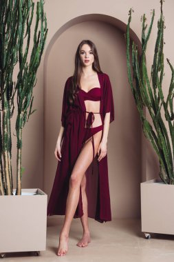 Siyah elbiseli güzel bir kadın sandalyede poz veriyor.