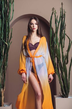 Stüdyoda poz veren şık elbiseli güzel genç bir kadın.