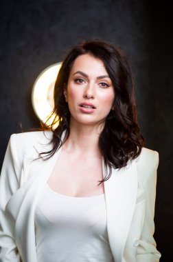 Beyaz takım elbiseli, bol saçlı ve makyajlı bir kız. Moda stili stüdyo boy portresi. Zarif, zarif bir kadın.