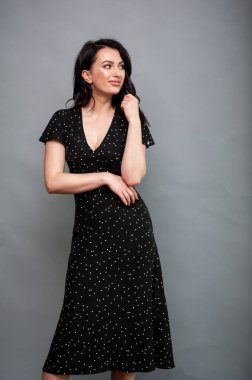 Uzun siyah yaz elbisesi içinde gülümseyen çekici bir kadın.