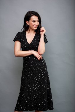 Uzun siyah yaz elbisesi içinde gülümseyen çekici bir kadın.