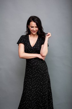 Uzun siyah yaz elbisesi içinde gülümseyen çekici bir kadın.