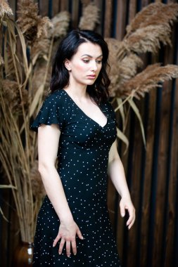 Uzun siyah yaz elbisesi içinde gülümseyen çekici bir kadın.