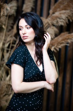 Uzun siyah yaz elbisesi içinde gülümseyen çekici bir kadın.