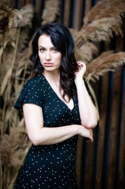 Uzun siyah yaz elbisesi içinde gülümseyen çekici bir kadın.