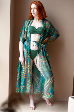 Stüdyoda poz veren şık elbiseli güzel bir genç kadın.