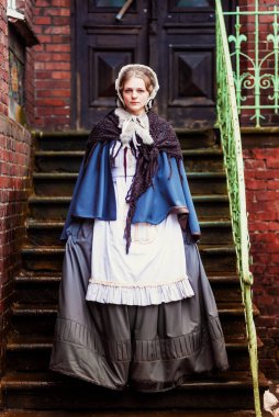 Eski şehirde yürüyen genç bir Victoria kadınının açık hava portresi