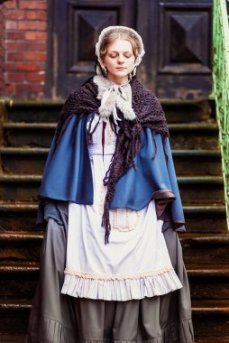 Eski şehirde yürüyen genç bir Victoria kadınının açık hava portresi