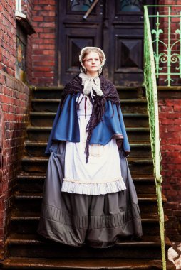 Eski şehirde yürüyen genç bir Victoria kadınının açık hava portresi