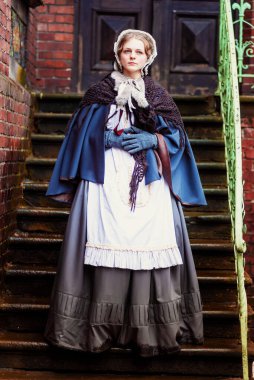 Eski şehirde yürüyen genç bir Victoria kadınının açık hava portresi