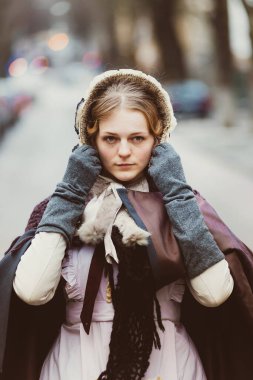 Eski şehirde yürüyen genç bir Victoria kadınının açık hava portresi