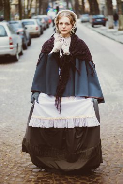 Eski şehirde yürüyen genç bir Victoria kadınının açık hava portresi