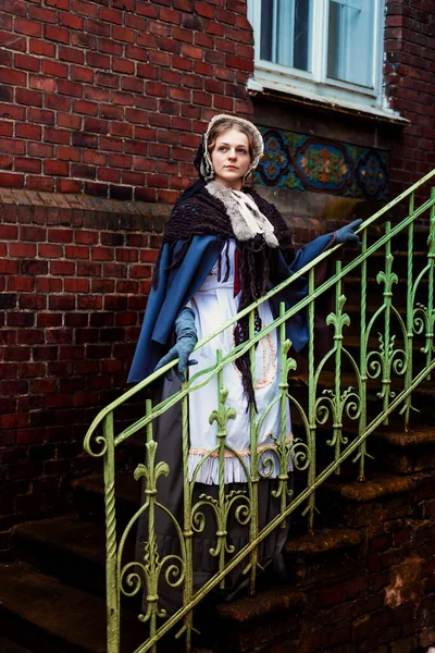 Outdoors portrait of a young victorian woman walking old city