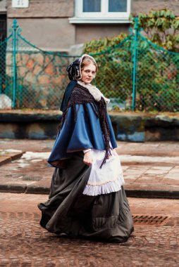 Eski şehirde yürüyen genç bir Victoria kadınının açık hava portresi