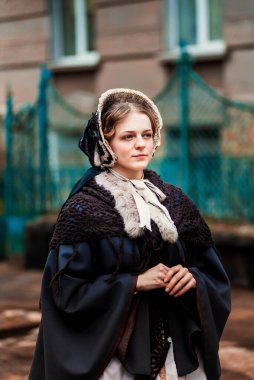 Eski şehirde yürüyen genç bir Victoria kadınının açık hava portresi