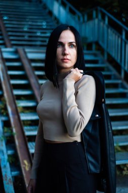 Siyah ceketli güzel bir kadının portresi ve bir binanın arka planında mavi bir elbise.