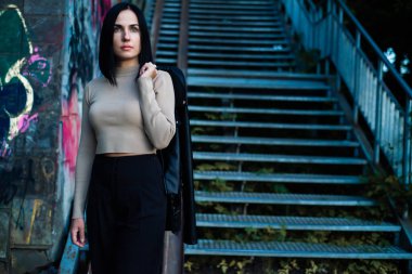 Siyah ceketli, mavi gömlekli ve arka planda eşarp takan güzel bir kadın.