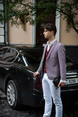 young handsome man in a suit and sunglasses standing near the window