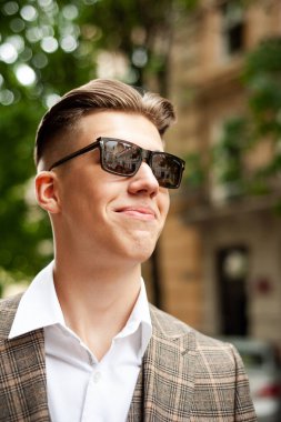  Güneş gözlüklü yakışıklı genç adam poz veriyor. 