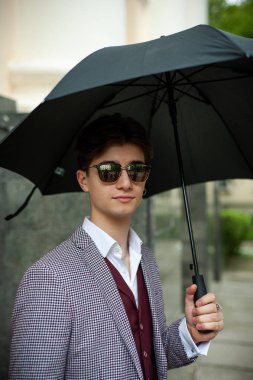 Şehirde şemsiyeli genç bir adam 