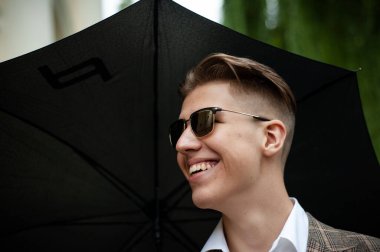 Şehirde şemsiyeli genç bir adam 