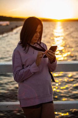 Kumsalda akıllı telefon kullanan genç bir kadın.