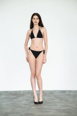 Siyah mayolu güzel bir kız portresi ve beyaz arka planda siyah iç çamaşırı.