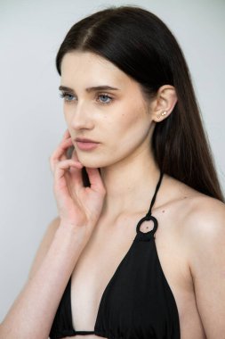 Stüdyoda poz veren siyah saçlı güzel bir genç kadın.