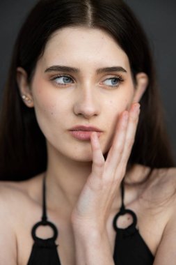 Koyu arkaplanda güzel küpeleri olan genç bir kadının portresi.