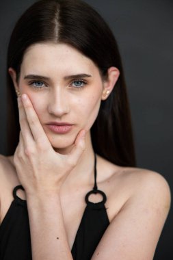 Siyah arka planı olan siyah gömlekli genç bir kadın.