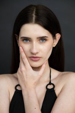 Stüdyoda siyah arka planda poz veren siyah saçlı güzel bir kadın.