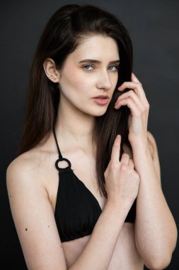 Boynunda siyah bir makyajı ve koyu bir geçmişi olan genç bir kadının portresi.