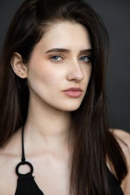 Koyu renk saçlı ve siyah makyajlı esmer bir kadının portresi koyu mavi gözlü.