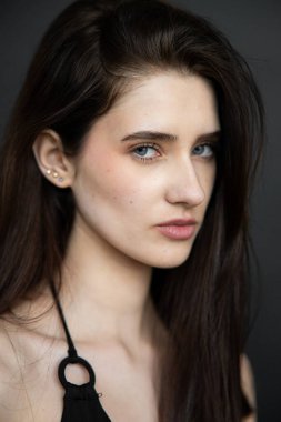 Karanlık bir stüdyoda poz veren esmer bir kız.