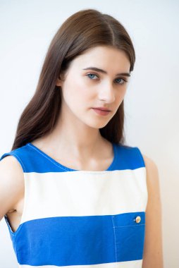 Beyaz arka planda çizgili bir elbise giymiş güzel bir esmerin portresi.